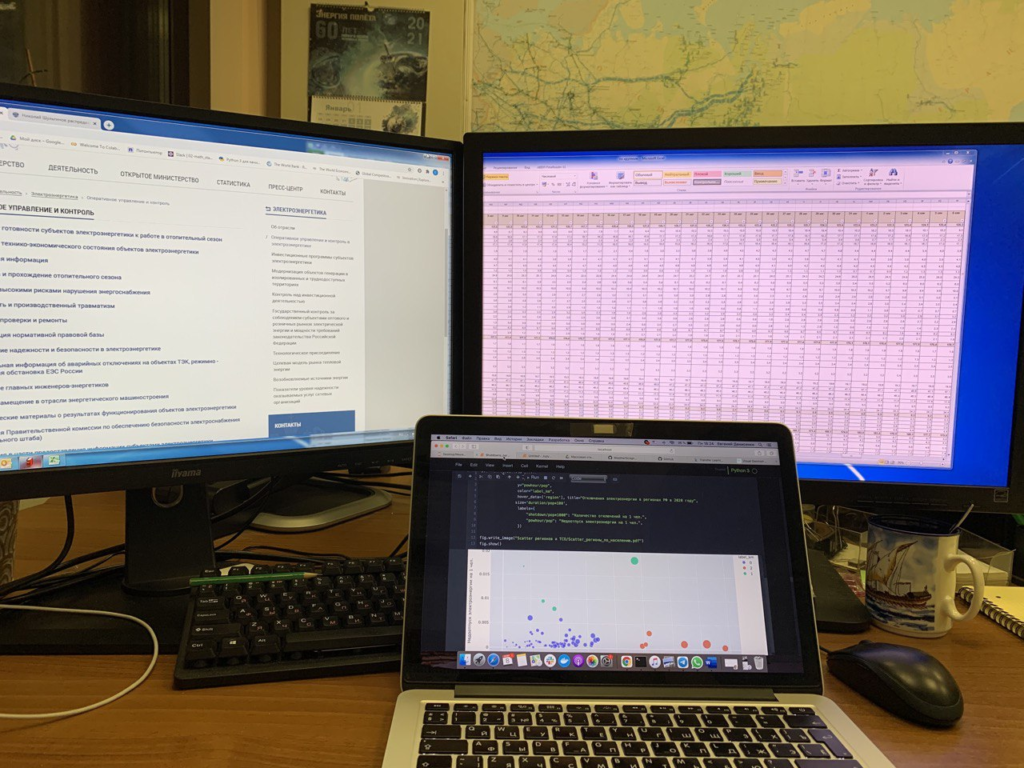 Ноутбук с кодом и два монитора с таблицами и данными